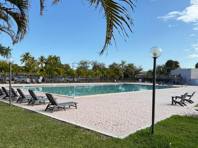 a view of a swimming pool with lawn chairs and couches