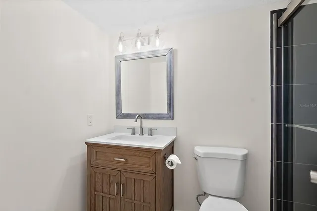 a bathroom with a toilet sink vanity and mirror