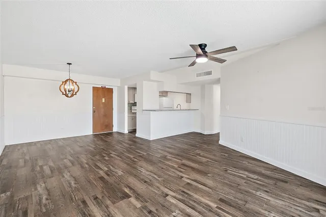 a view of empty room with wooden floor and ceiling fan