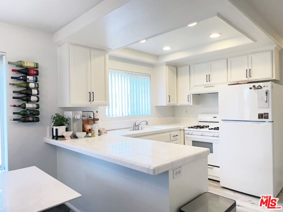 7864 Stewart And Gray Road Downey, CA 90241 - Photo 11 of 25 a kitchen with white cabinets and white appliances