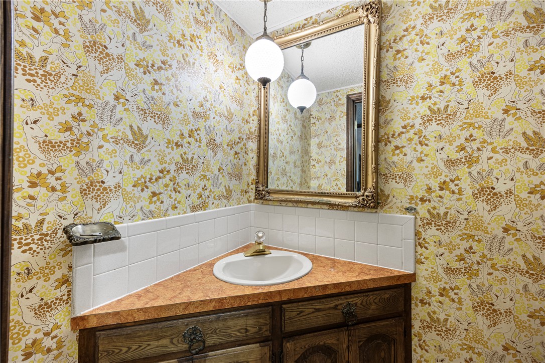 411 Marina Road Russellville, AR 72802 - Photo 37 of 49 Corner vanity featuring a white drop-in sink with a single-hole faucet, a wood-finish cabinet with decorative hardware, and a laminate countertop
