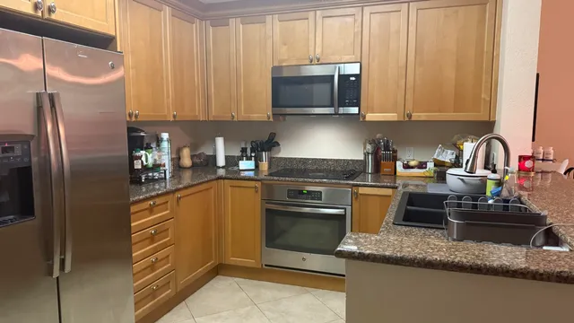 a kitchen with stainless steel appliances granite countertop a refrigerator a stove top oven a sink and dishwasher