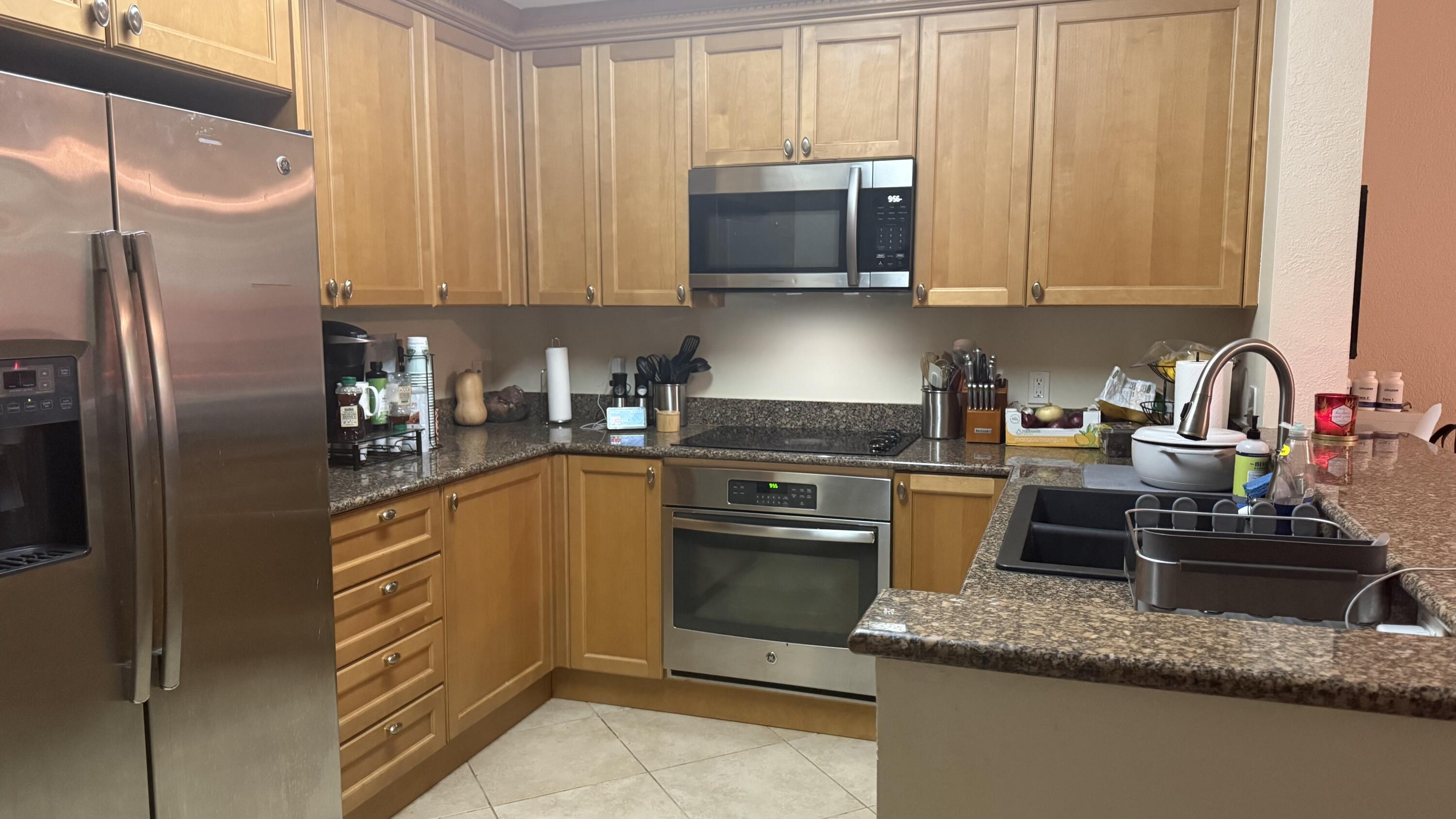 1690 Renaissance Commons Boulevard, Unit 1427 Boynton Beach, FL 33426 - Photo 1 of 20 a kitchen with stainless steel appliances granite countertop a refrigerator a stove top oven a sink and dishwasher