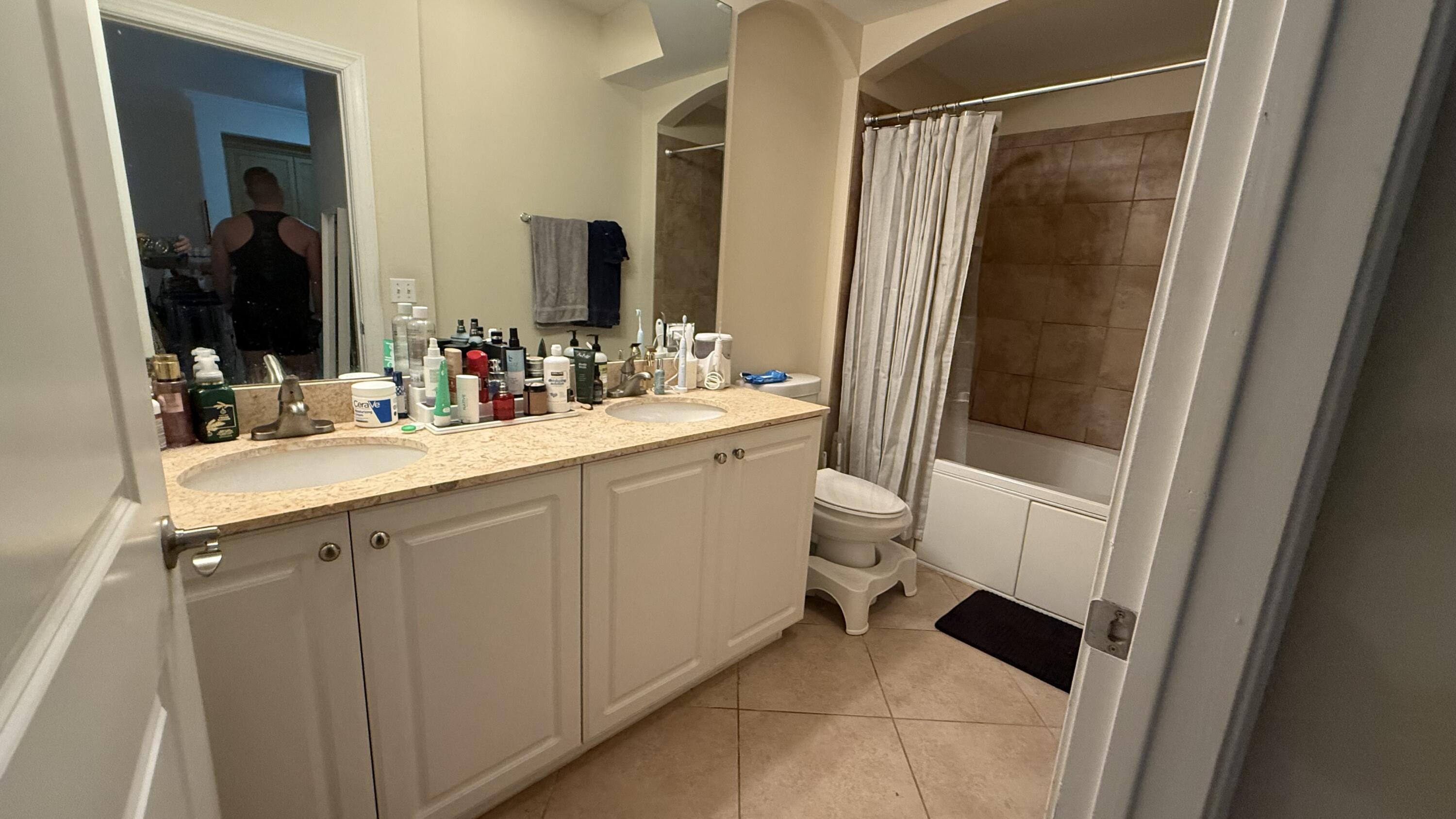 1690 Renaissance Commons Boulevard, Unit 1427 Boynton Beach, FL 33426 - Photo 18 of 20 a bathroom with a sink a toilet a mirror and shower