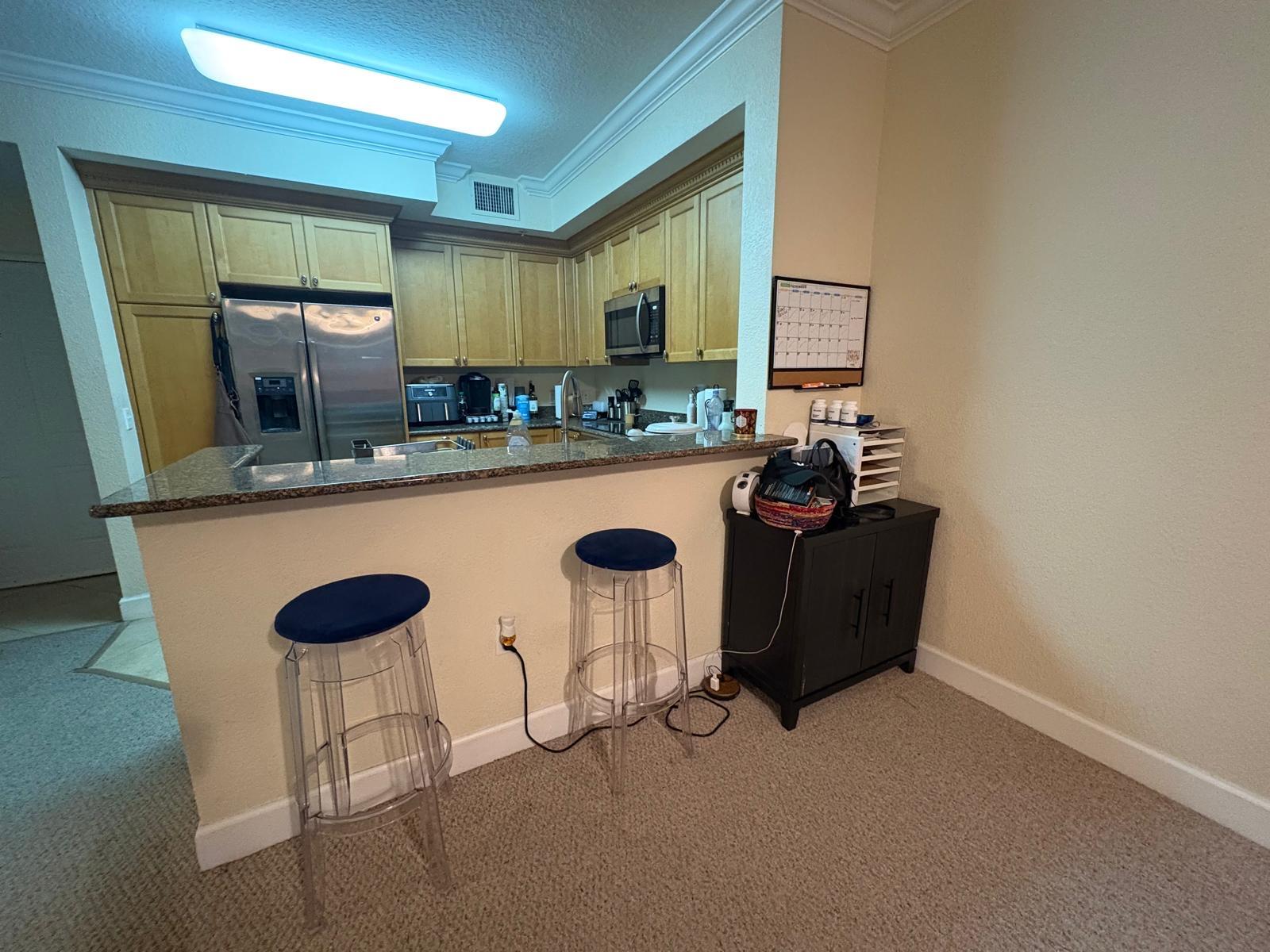 1690 Renaissance Commons Boulevard, Unit 1427 Boynton Beach, FL 33426 - Photo 7 of 20 a kitchen with a sink and chairs