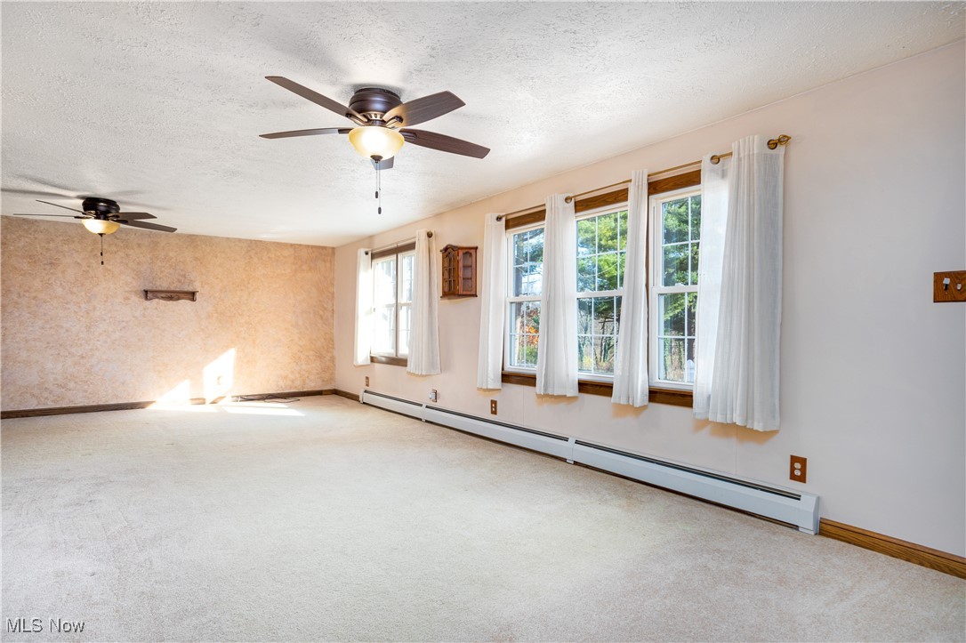 7384 South Cleveland Massillon Road Clinton, OH 44216 - Photo 14 of 35 Expansive carpeted living room with a baseboard radiator, a textured ceiling, and ceiling fan