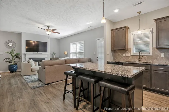 a kitchen with stainless steel appliances granite countertop a stove top oven a sink dishwasher a dining table and chairs with wooden floor