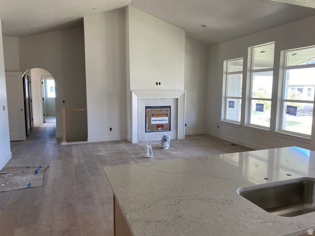 4676 West 75 North, Unit 401 West Point, UT 84015 - Photo 8 of 17 Spacious living area featuring a vaulted ceiling and a fireplace with a white mantel and tile surround