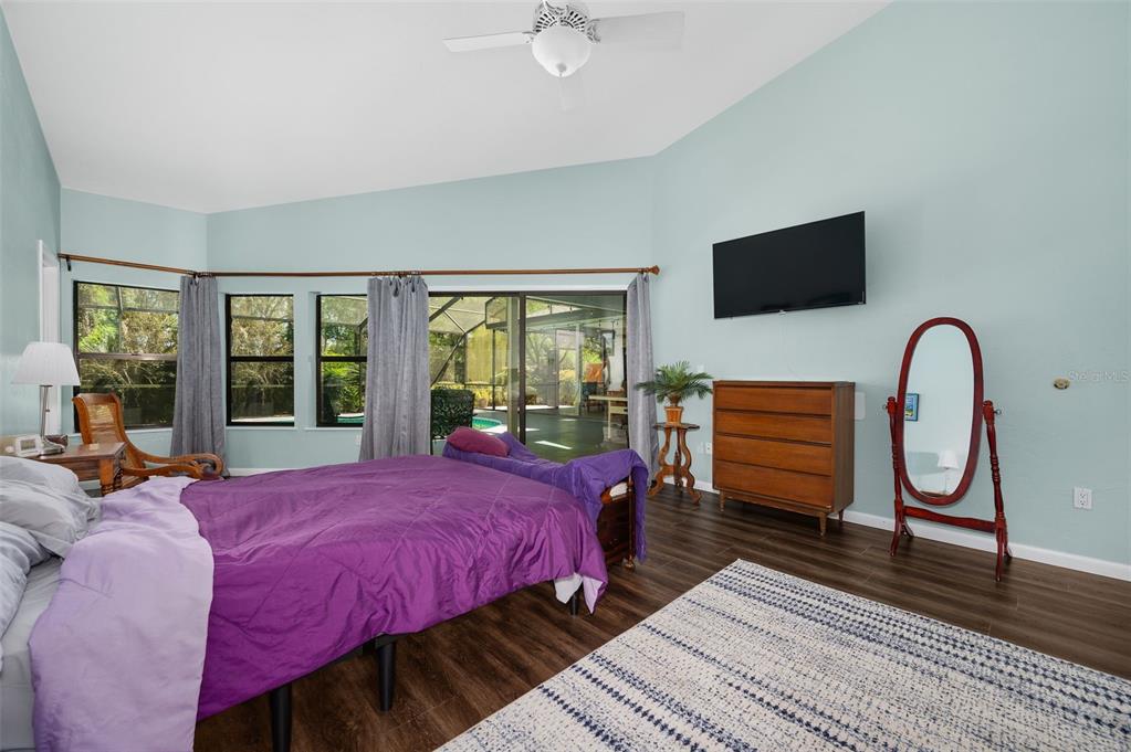 9923 Southwest 2nd Place Gainesville, FL 32607 - Photo 23 of 73 a bedroom with a bed a dresser next to a large window with wooden floor