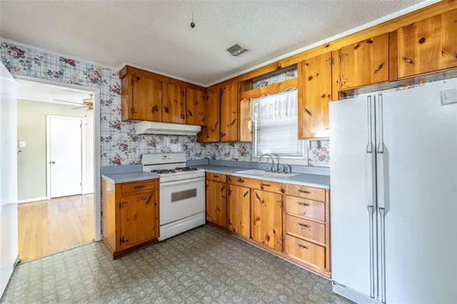 a kitchen with stainless steel appliances granite countertop a refrigerator a sink dishwasher and wooden cabinets with wooden floor