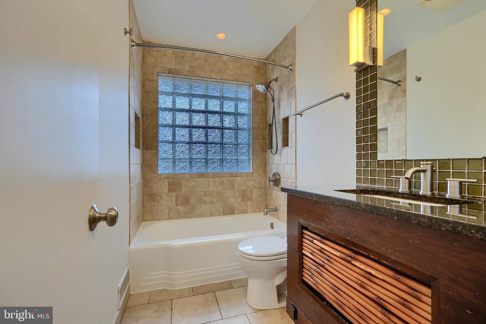 9715 Saxony Road Silver Spring, MD 20910 - Photo 15 of 31 a bathroom with a granite countertop bathtub shower sink vanity and toilet