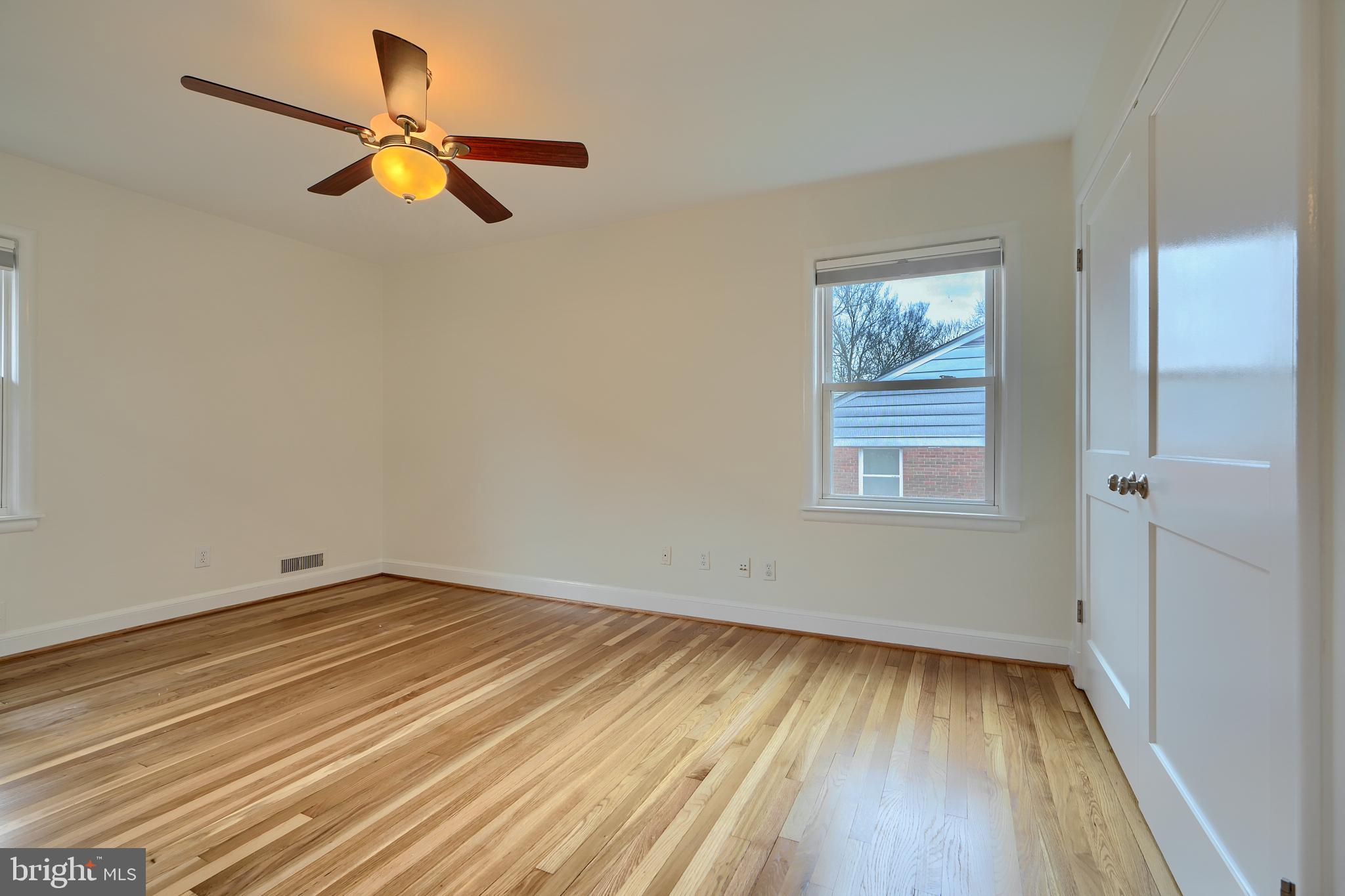 9715 Saxony Road Silver Spring, MD 20910 - Photo 17 of 31 an empty room with wooden floor closet and windows