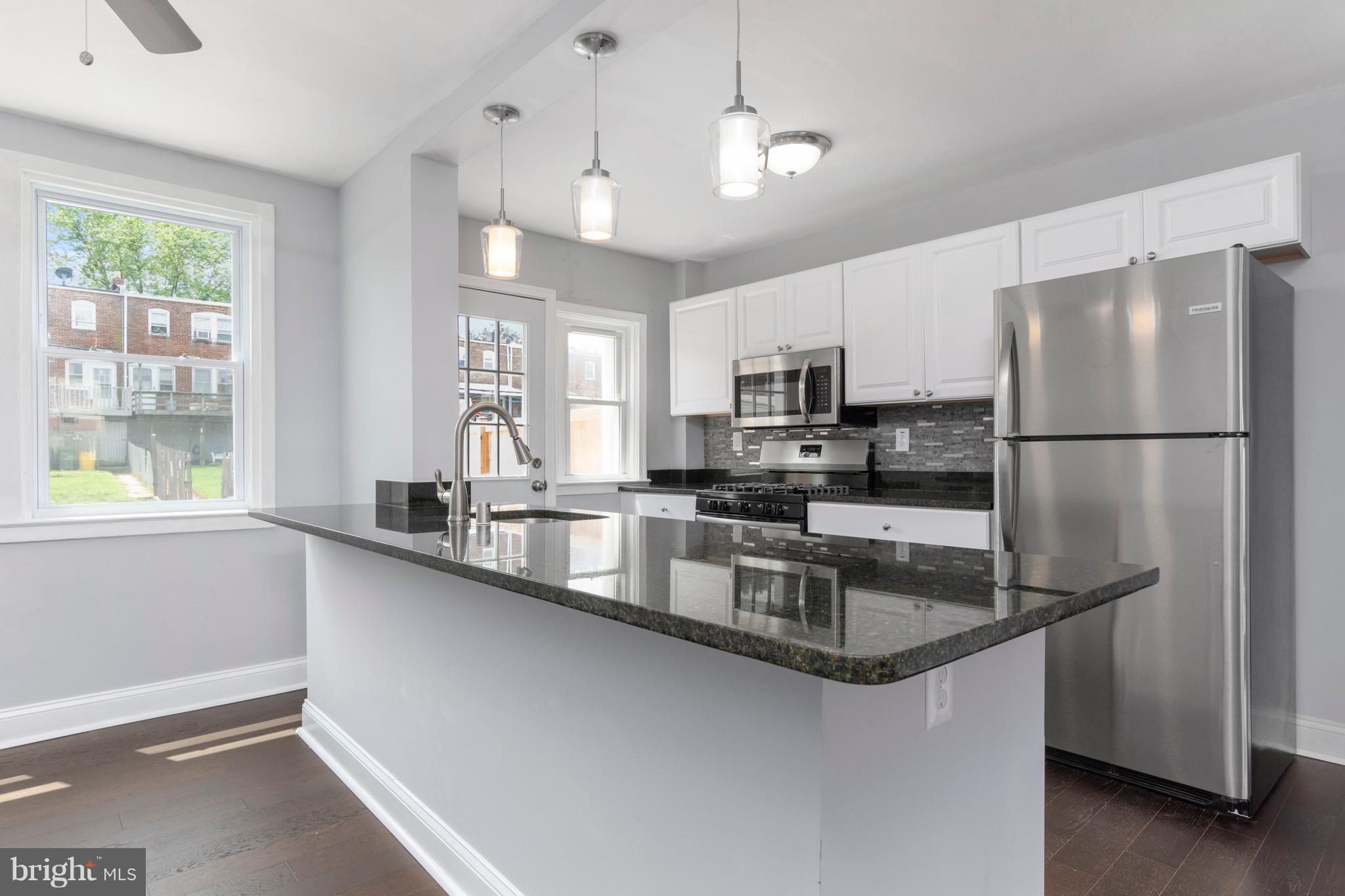 209 West Meadow Road Baltimore, MD 21225 - Photo 7 of 29 a kitchen with stainless steel appliances granite countertop a refrigerator a sink a stove and a sink with wooden floor