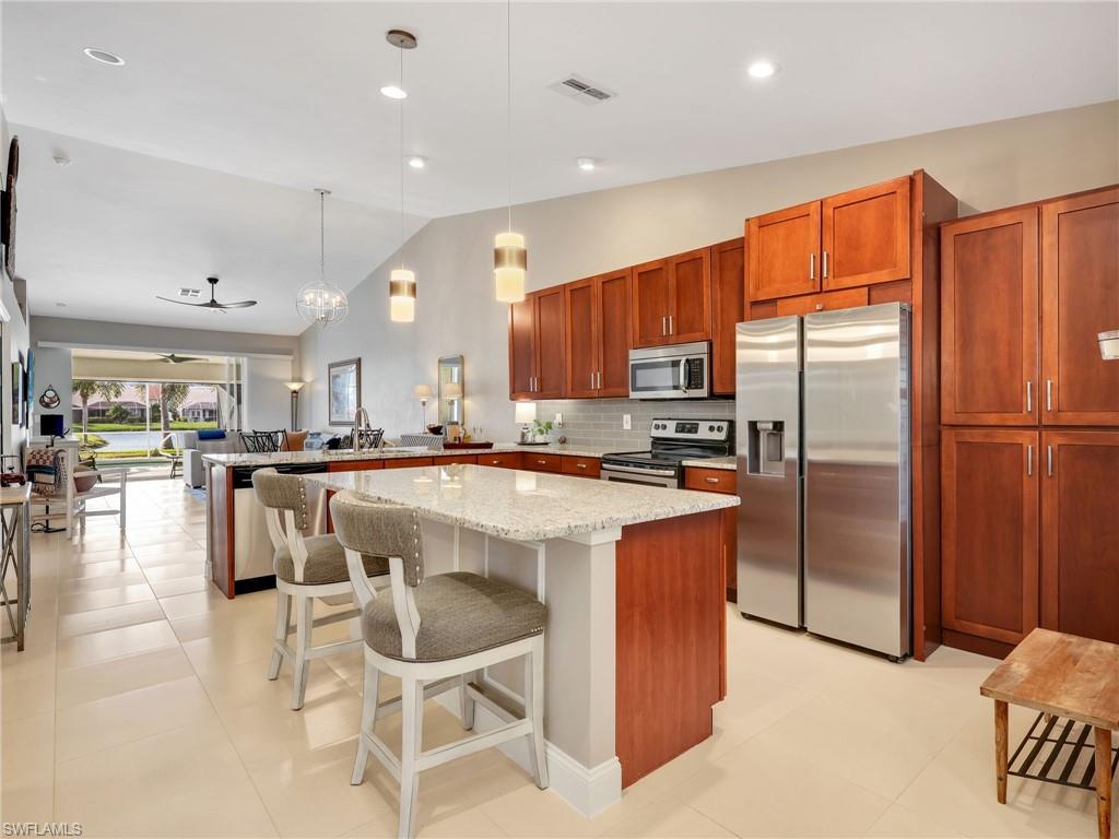 2214 Stacil Circle, Unit 27 Naples, FL 34109 - Photo 5 of 39 a kitchen with stainless steel appliances granite countertop a refrigerator a stove a sink a dining table and chairs with wooden floor
