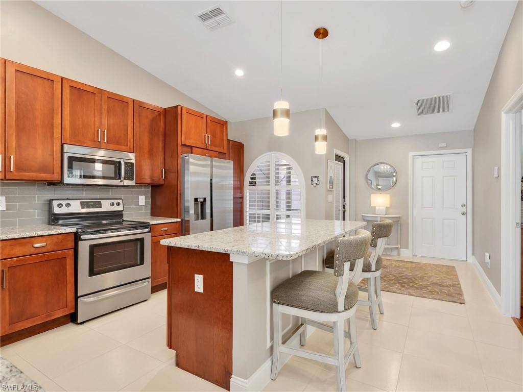 2214 Stacil Circle, Unit 27 Naples, FL 34109 - Photo 6 of 39 a kitchen with stainless steel appliances granite countertop a stove top oven a sink dishwasher a dining table and chairs with wooden floor