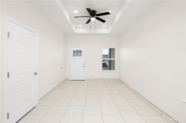 an empty room with chandelier fan and windows