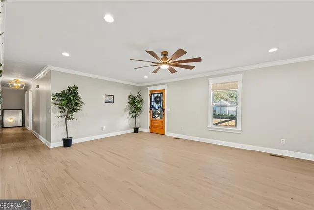 an empty room with windows and chandelier fan