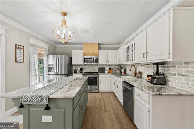 a kitchen with granite countertop stainless steel appliances a stove a sink a refrigerator cabinets and furniture