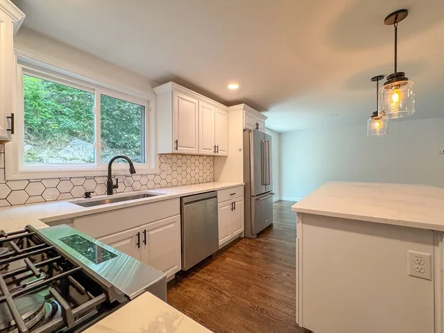 a kitchen that has a sink and a stove with wooden floor