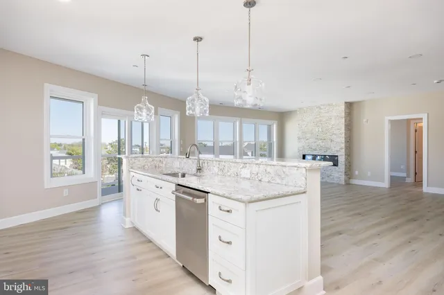 a kitchen with stainless steel appliances granite countertop a sink a window and a wooden floor
