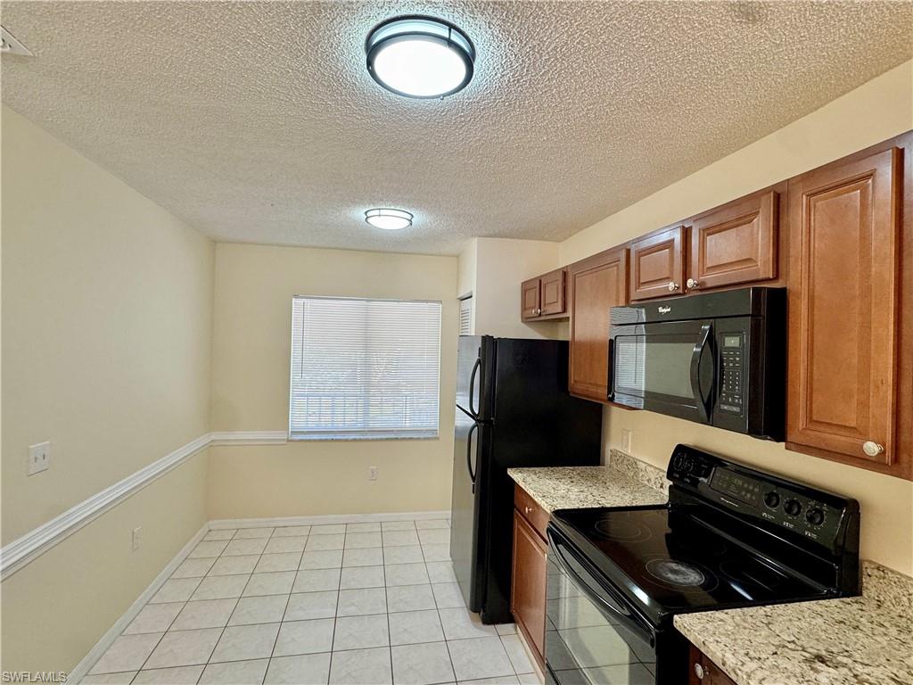 5665 Whitaker Road, Unit A201 Naples, FL 34112 - Photo 11 of 30 a kitchen with a refrigerator and a stove