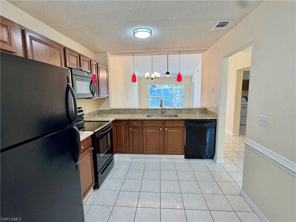 5665 Whitaker Road, Unit A201 Naples, FL 34112 - Photo 12 of 30 a kitchen with stainless steel appliances granite countertop a sink counter space and cabinets