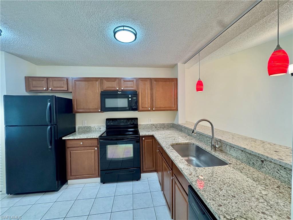 5665 Whitaker Road, Unit A201 Naples, FL 34112 - Photo 3 of 30 a kitchen with granite countertop a sink and a stove