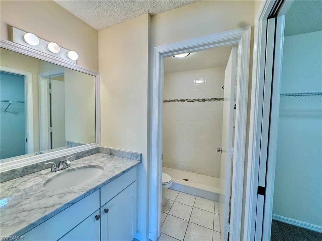 5665 Whitaker Road, Unit A201 Naples, FL 34112 - Photo 7 of 30 a bathroom with a granite countertop sink shower and a mirror