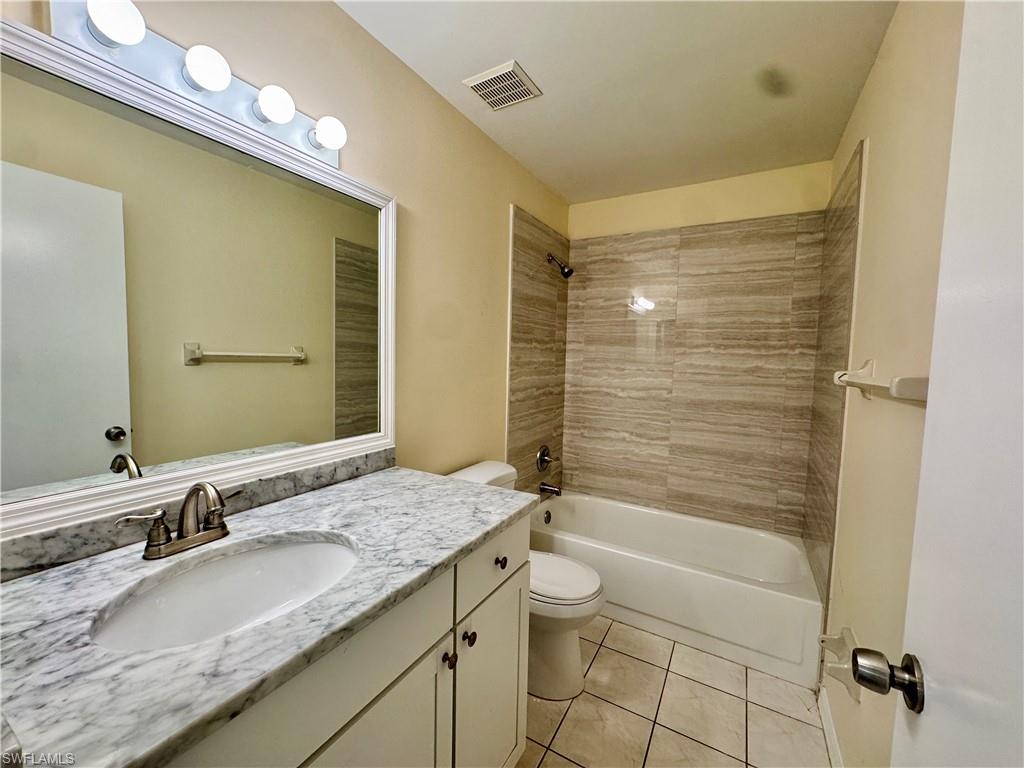 5665 Whitaker Road, Unit A201 Naples, FL 34112 - Photo 10 of 30 a bathroom with a granite countertop sink a toilet and shower
