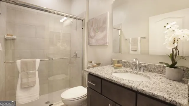 a bathroom with a granite countertop sink a toilet and shower