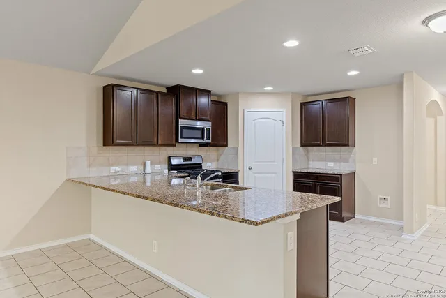 a large kitchen with granite countertop a large counter top stainless steel appliances and cabinets