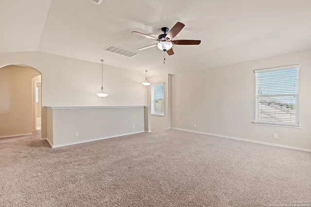 an empty room with windows and fan