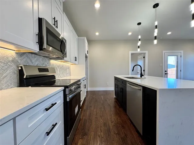 a large kitchen with stainless steel appliances a large counter top a stove and a sink