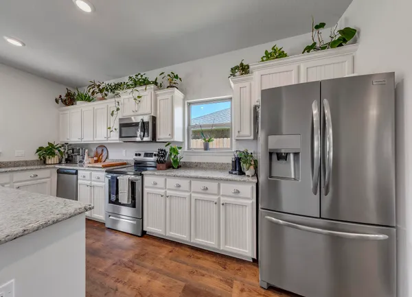 a kitchen with stainless steel appliances granite countertop a refrigerator a stove a sink a stove a dining table and chairs