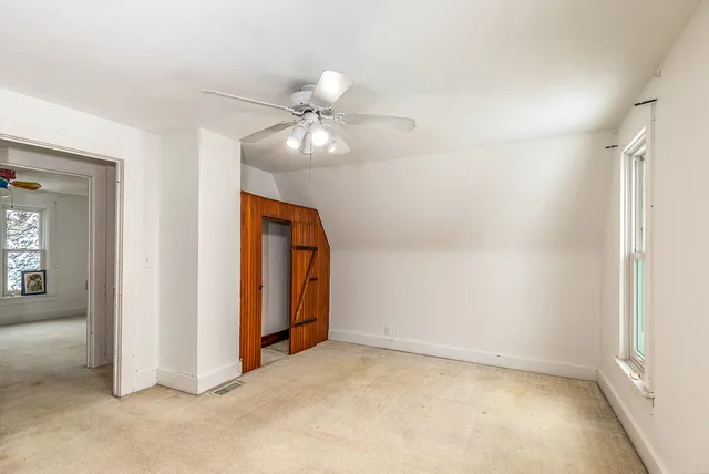 an empty room with closet and a chandelier fan