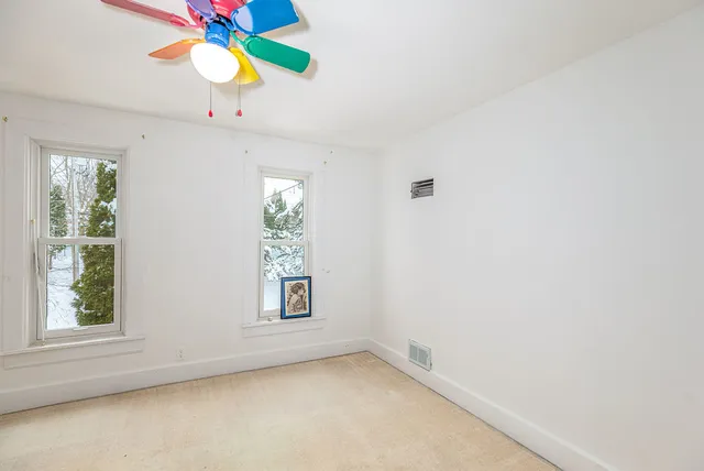 an empty room with windows and chandelier fan