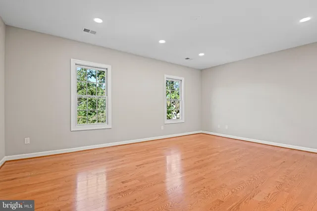 a view of a hallway with wooden floor and a bathroom