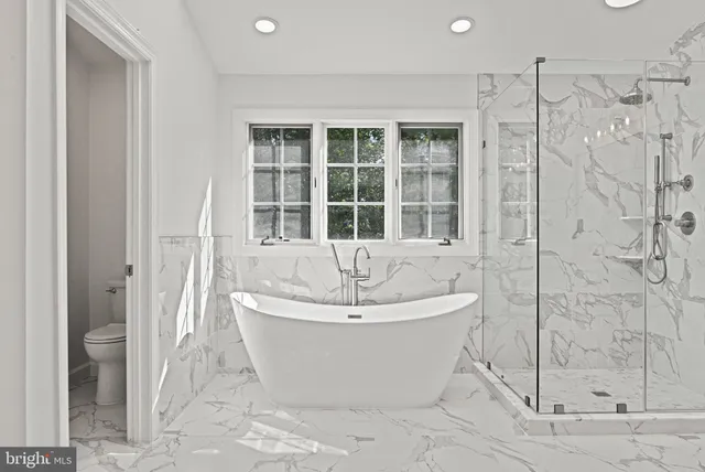 a spacious bathroom with a tub sink and mirror