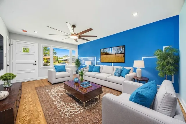 a living room with furniture a rug potted plant and a window