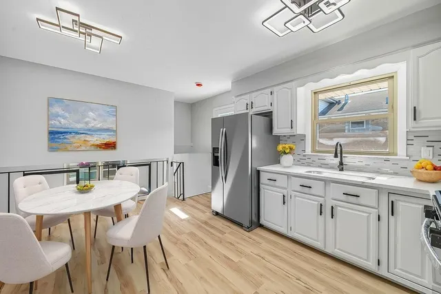 a kitchen with stainless steel appliances granite countertop a dining table chairs refrigerator and cabinets