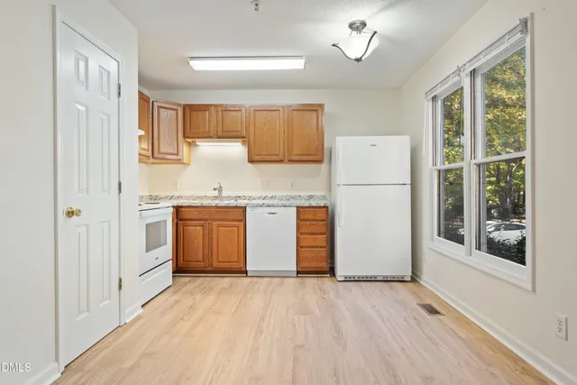 a kitchen with a white cabinets and wooden floor