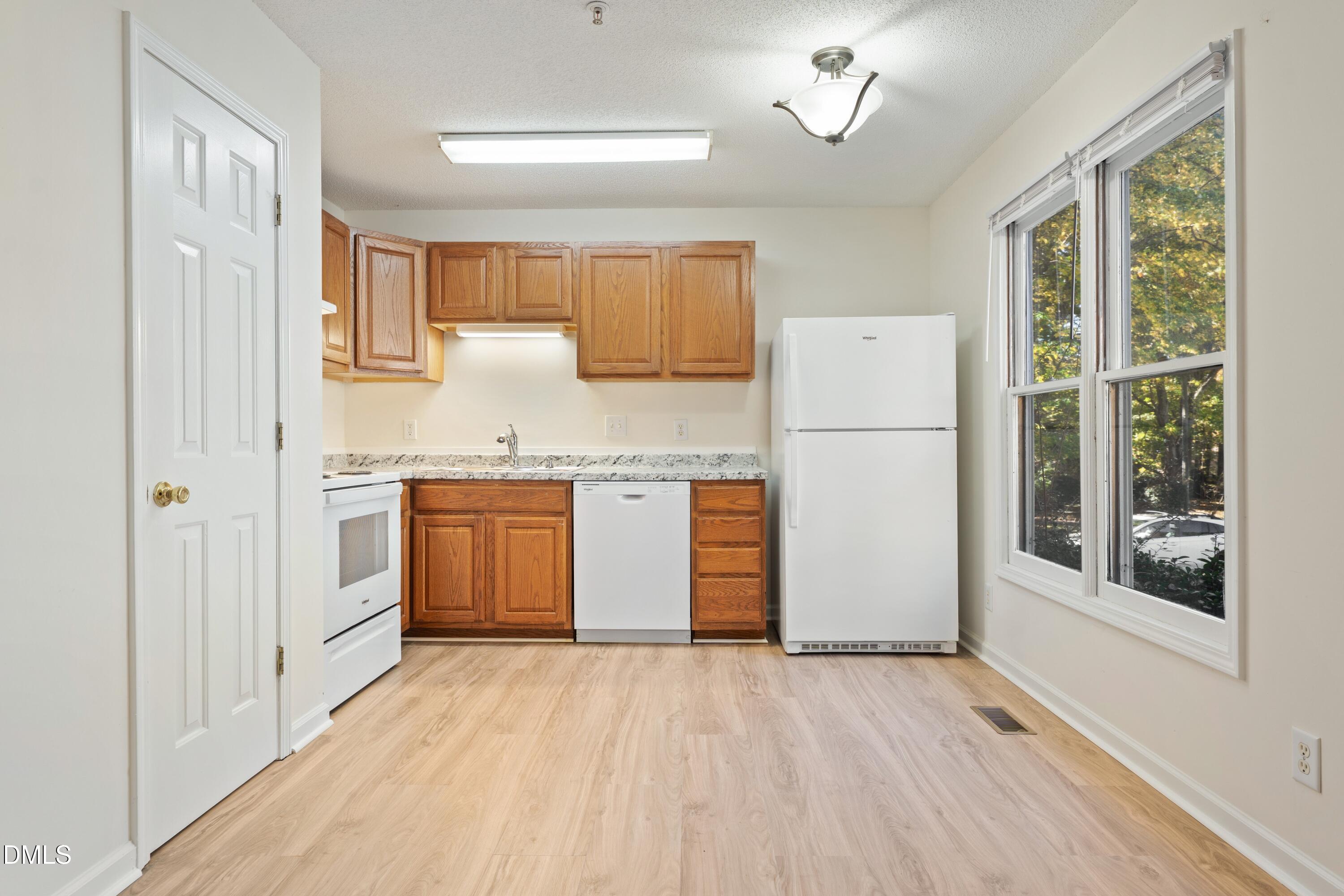 121 Westview Drive, Unit 33 Carrboro, NC 27510 - Photo 5 of 13 a kitchen with a white cabinets and wooden floor