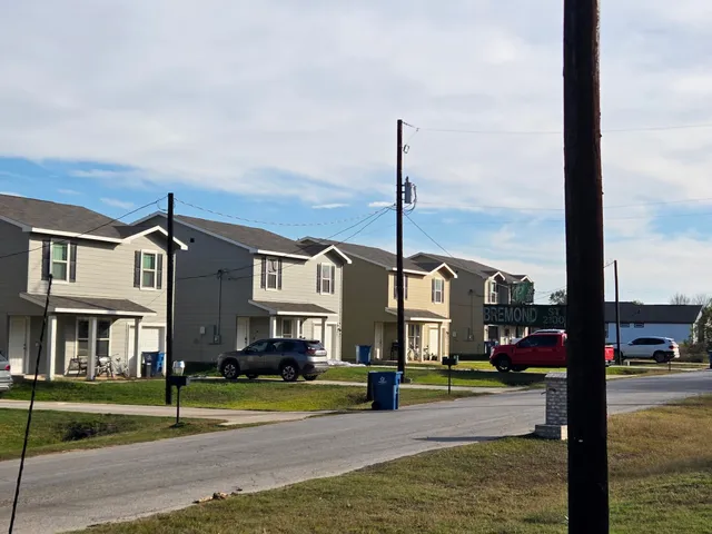 a front view of residential houses with yard and road