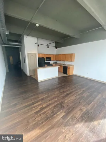 a kitchen with stainless steel appliances wooden floor and a refrigerator