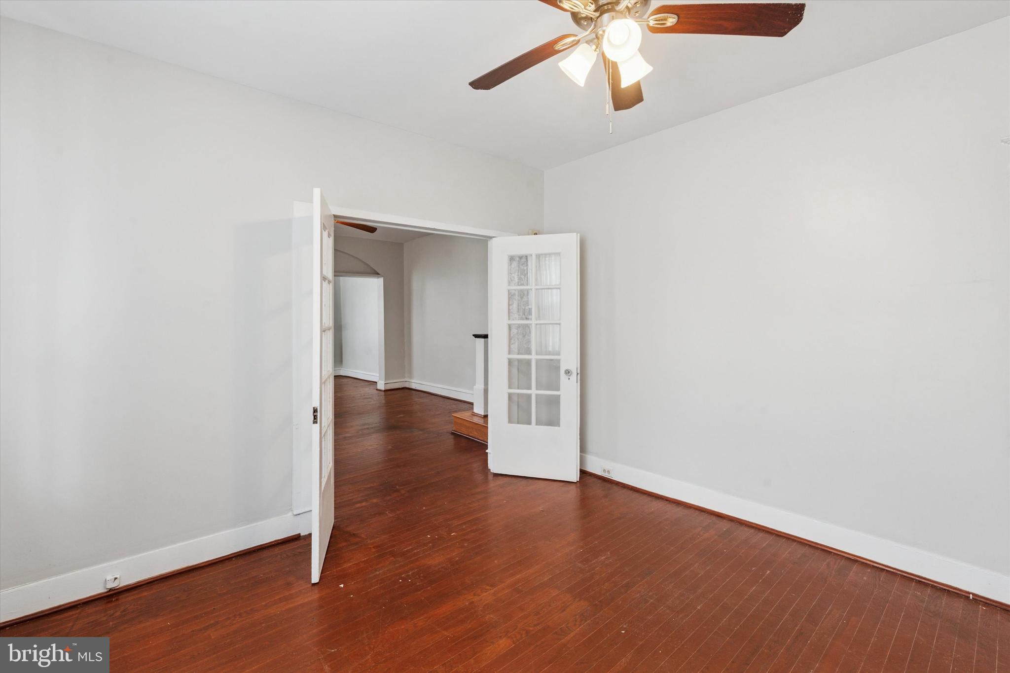 124 Arnold Road Ardmore, PA 19003 - Photo 9 of 24 an empty room with wooden floor chandelier fan and windows