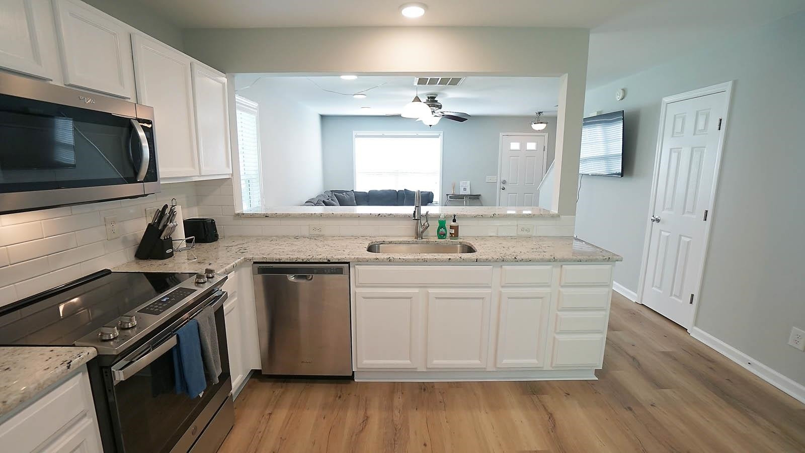 4305 Chimney Stone Road Durham, NC 27704 - Photo 4 of 21 a kitchen with stainless steel appliances a sink dishwasher stove and microwave with wooden floor