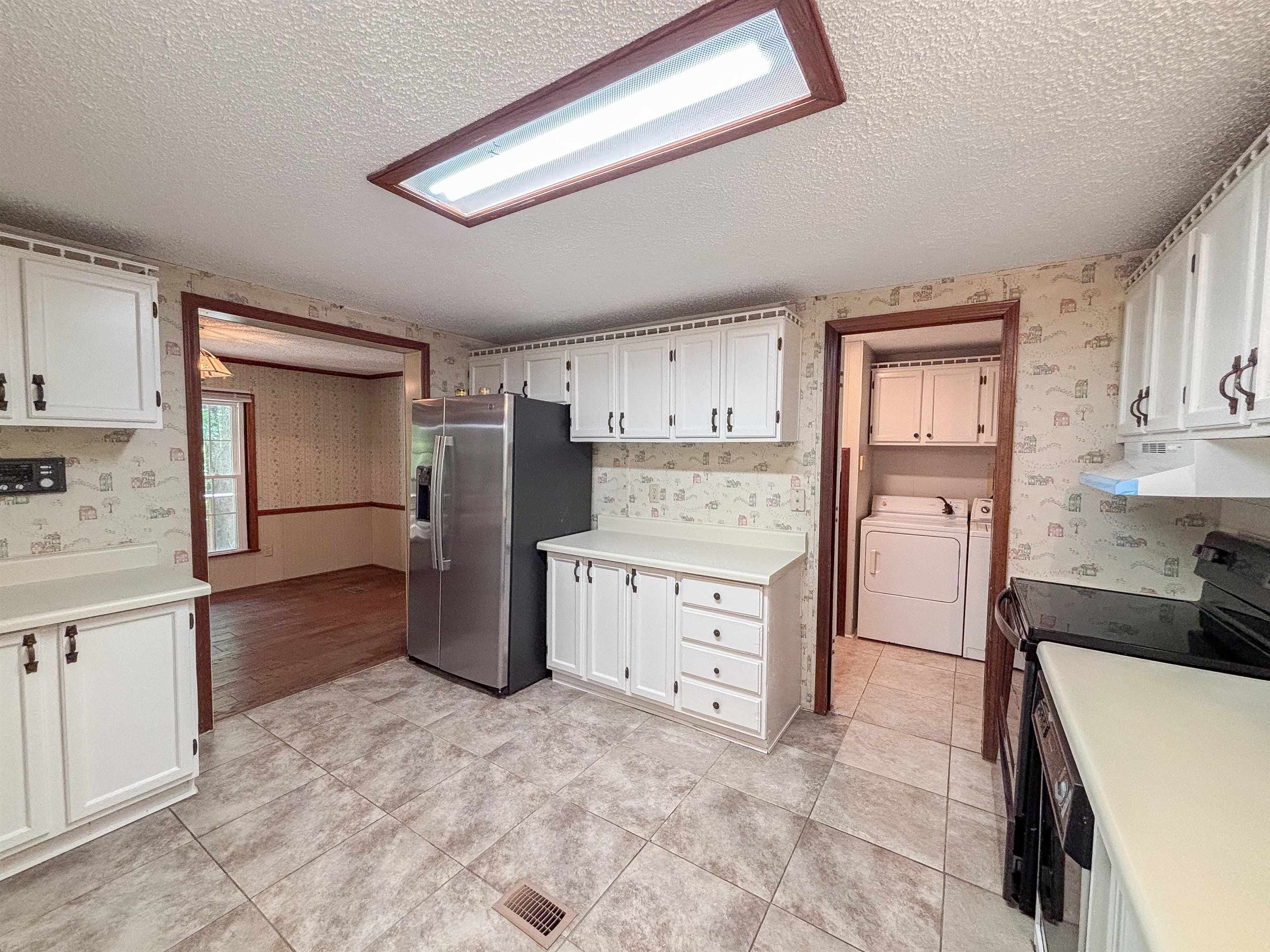 471 Milton Road Millington, TN 38053 - Photo 6 of 30 White cabinetry with dark hardware, a stainless steel refrigerator, and tiled flooring