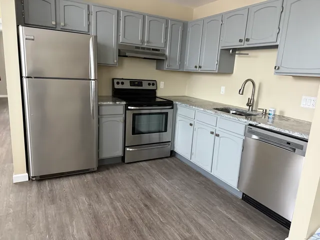 a kitchen with a sink a refrigerator and cabinets