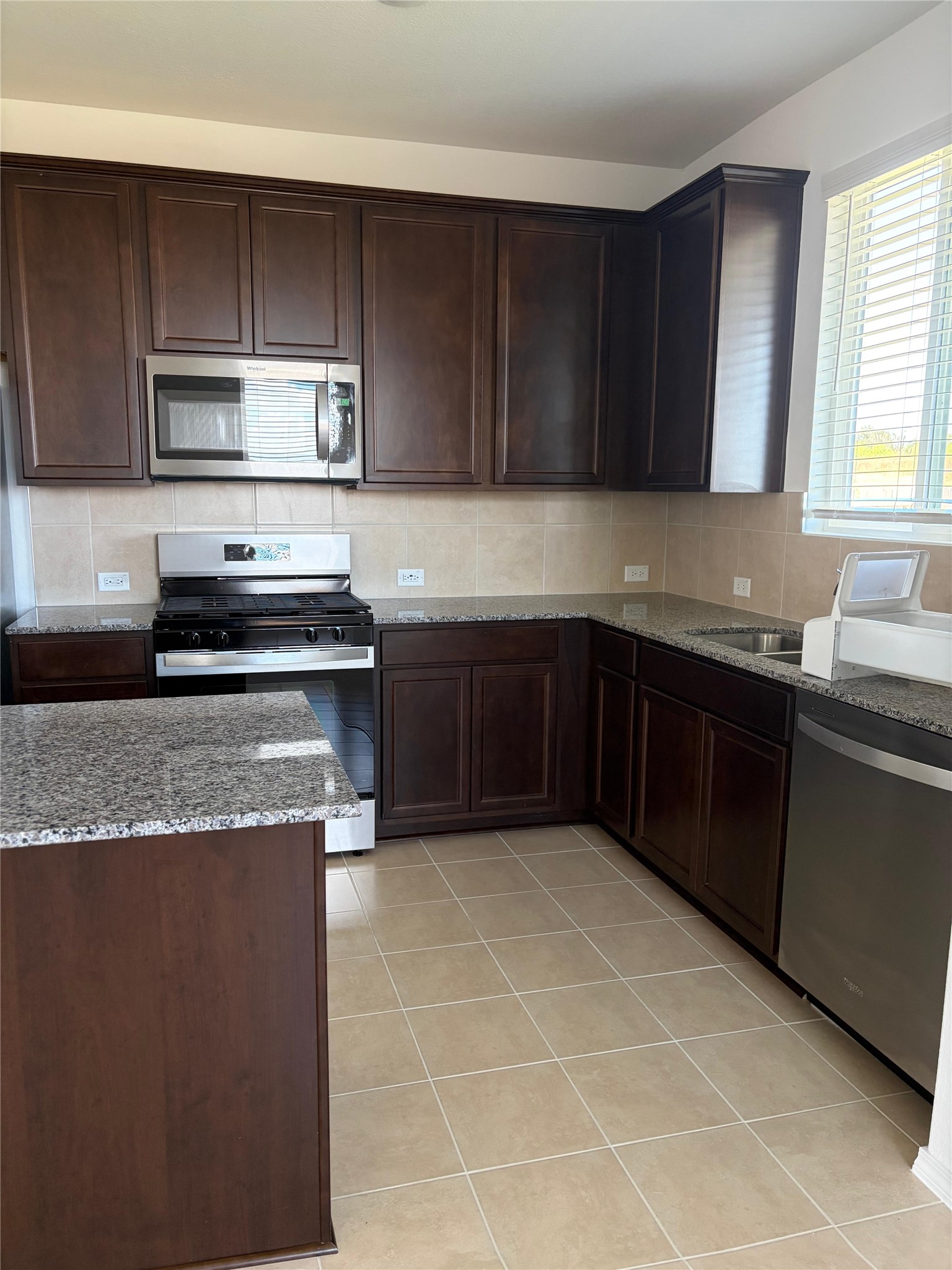 545 Henry Milton Road Georgetown, TX 78626 - Photo 29 of 33 Rich dark wood cabinetry pairs beautifully with granite countertops and tiled flooring.