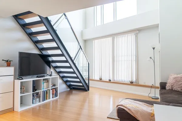 a view of an empty room with wooden floor and stairs